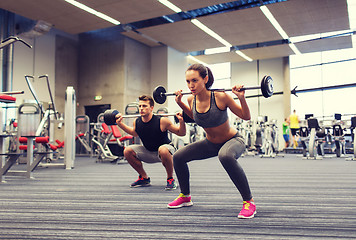 Image showing young man and woman training with barbell in gym