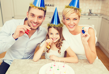 Image showing smiling family in blue hats blowing favor horns