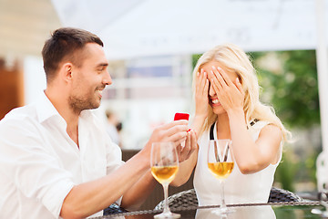 Image showing happy couple with engagement ring and wine at cafe