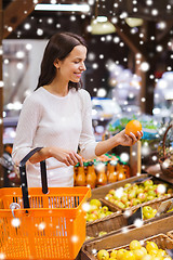 Image showing happy young woman with food basket in market