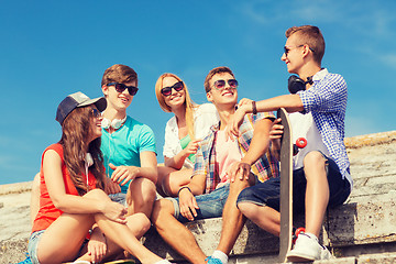 Image showing group of smiling friends sitting on city street