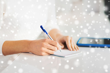 Image showing close up of hands with pen writing to notepad