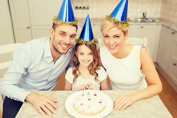 Image showing smiling family in blue hats with cake