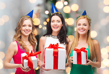 Image showing smiling women in party caps with gift boxes