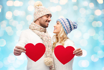 Image showing smiling couple in winter clothes with red hearts