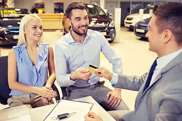 Image showing happy couple with car dealer in auto show or salon