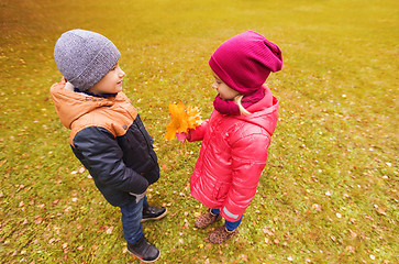 Image showing little boy giving autumn maple leaves to girl