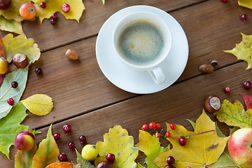 Image showing close up of coffee cup on table with autumn leaves