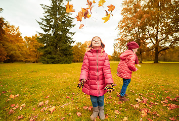 Image showing happy children playing with autumn leaves in park