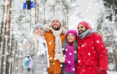 Image showing smiling friends with smartphone in winter forest