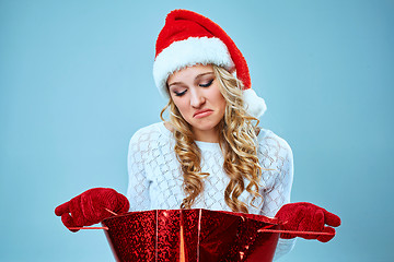 Image showing Frustrated and annoyed beautiful young woman in Santa Claus hat