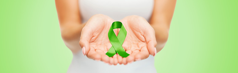 Image showing close up of hands holding green awareness ribbon