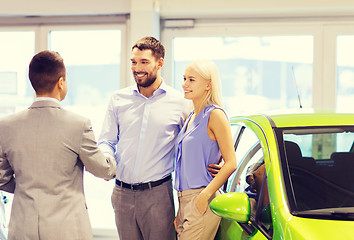 Image showing happy couple with car dealer in auto show or salon