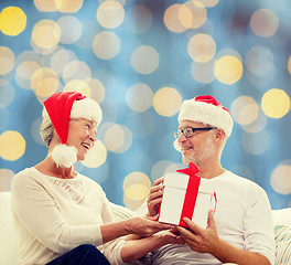 Image showing happy senior couple with gift box at home