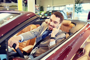 Image showing happy man sitting in car at auto show or salon