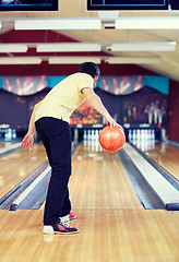 Image showing happy young man throwing ball in bowling club