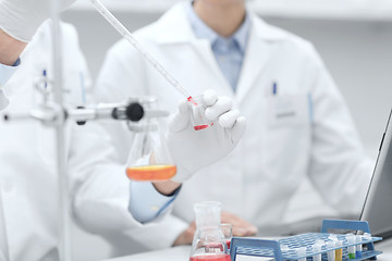 Image showing close up of scientists filling test tube in lab