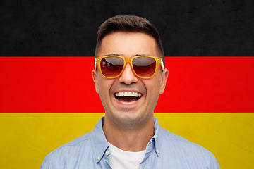 Image showing face of smiling man in sunglasses over german flag