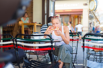 Image showing Woman eating pizza outdoor in cafeteria.