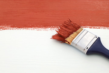 Image showing Paintbrush with red paint, painting over white board