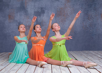 Image showing Three young ballerinas posing on the floor 