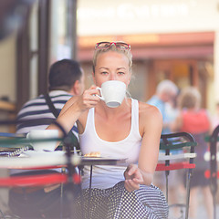 Image showing Woman drinking coffee outdoor on street.