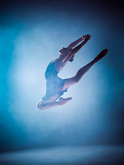 Image showing The silhouette of young ballet dancer jumping on a blue backgrou