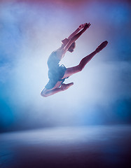 Image showing The silhouette of young ballet dancer jumping on a blue backgrou