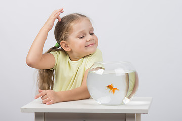 Image showing Four-year girl make a wish while enjoying a goldfish in an aquarium