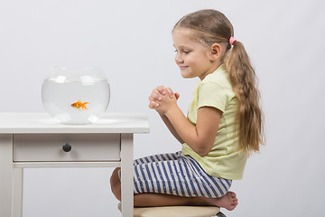 Image showing Four-year girl makes a wish sitting in front of a goldfish