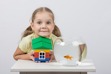 Image showing Four-year girl holding a toy house and sits in front of a goldfish