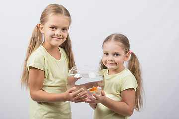 Image showing Two girls holding hands in an aquarium with goldfish