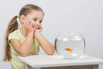 Image showing Four-year girl admires a goldfish in an aquarium