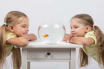 Image showing Two girls looking at a goldfish in a small fishbowl