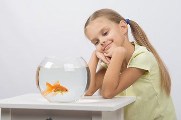 Image showing Thoughtful girl dreaming and looking at goldfish