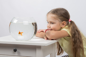 Image showing Thoughtful and dreams of a girl sitting in front of a goldfish