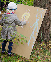 Image showing Little girl drawing with crayons on cardboard