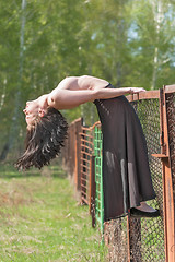 Image showing Attractive topless woman relaxes on grid fence