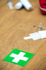 Image showing First aid kit and green cross on a wooden surface