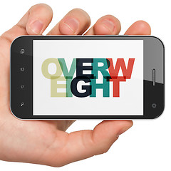 Image showing Health concept: Hand Holding Smartphone with Overweight on  display