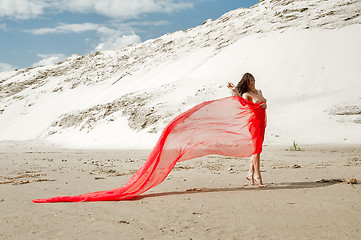 Image showing Attractive naked girl with red scarf on sand