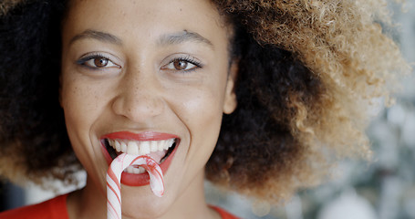 Image showing Fun young woman biting Christmas candy cane