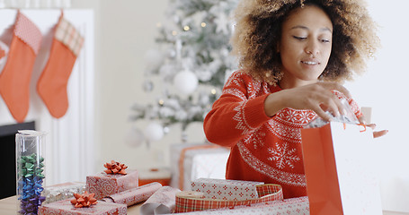 Image showing Pretty young woman wrapping Xmas presents