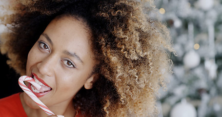 Image showing Sensuous young woman licking a striped candy cane