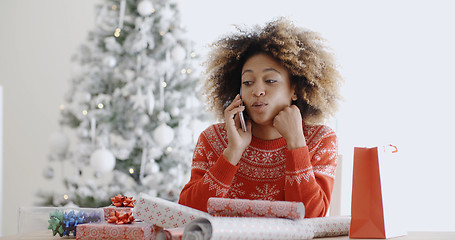 Image showing Young woman chatting on her mobile at Christmas