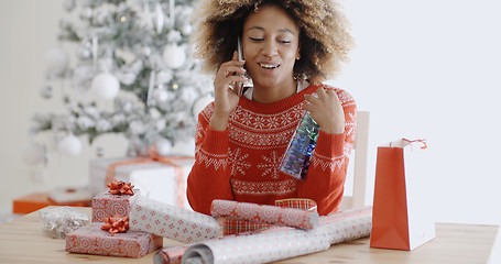 Image showing Woman chatting on a mobile as she wraps gifts