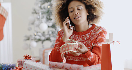 Image showing Young woman chatting on her mobile at Christmas