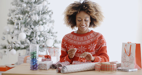 Image showing Happy young African woman wrapping presents