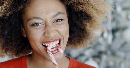 Image showing Fun young woman biting Christmas candy cane