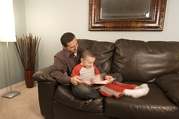Image showing Father and Son Reading a Book on the Couch